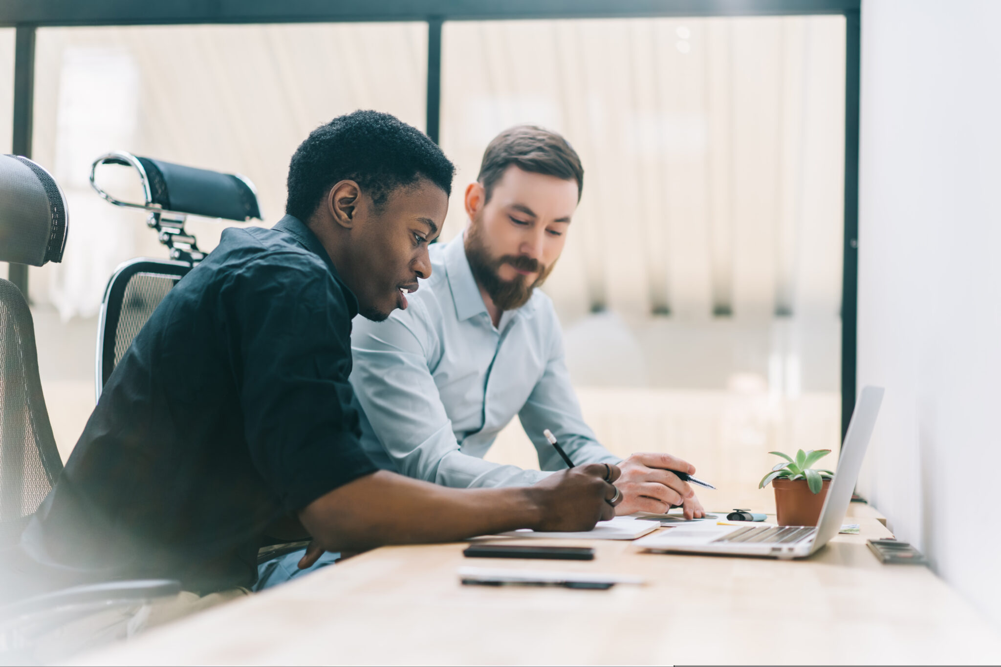 Pensive,African,American,Employee,Consulting,With,Colleague,Sitting,At,Modern